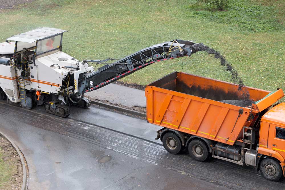Milling equipment removing the top layer of a worn asphalt surface