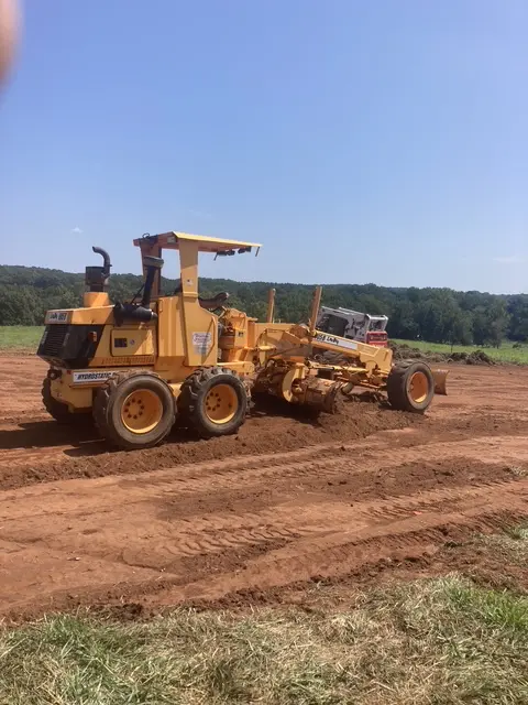 Large yellow construction vehicle preparing a dirt lot for asphalt