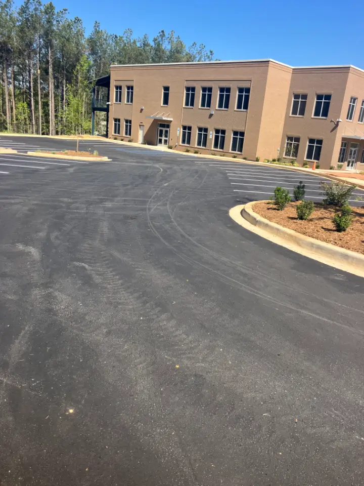 A freshly paved parking lot outside of a two-story building